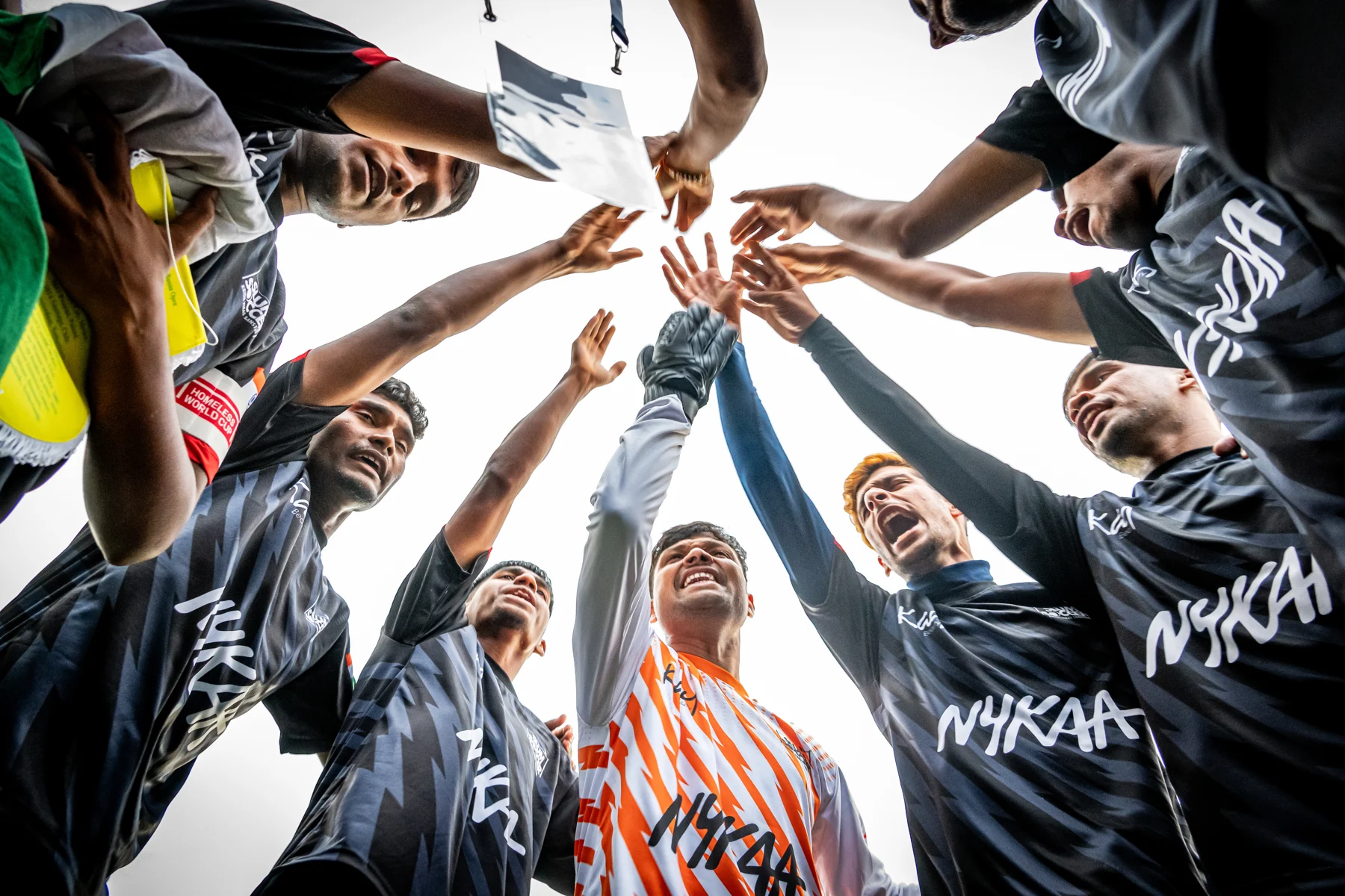 Players bring their hands together in a team huddle at the Oslo 2025 Homeless World Cup